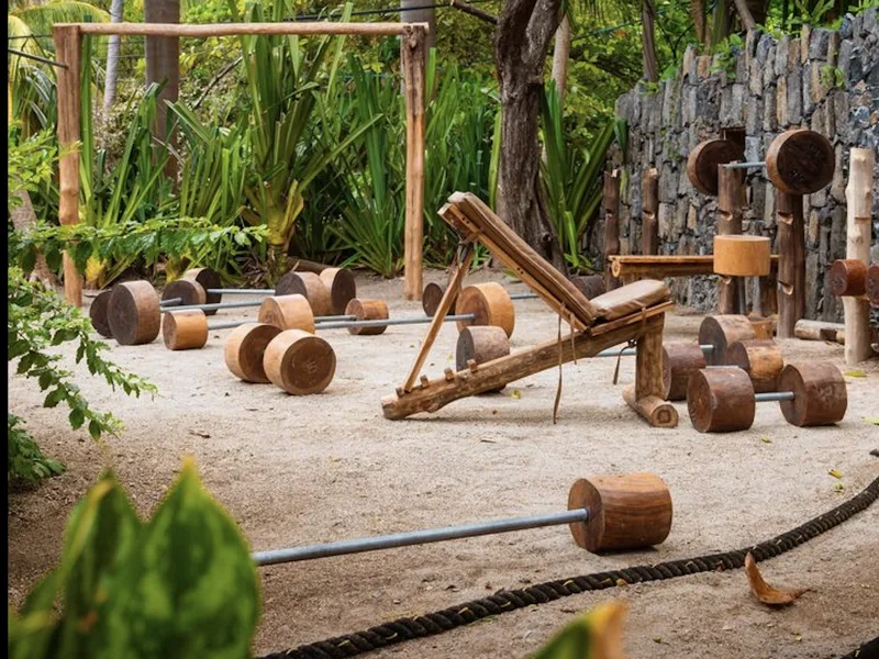 Timber weight rigs, log barbells and a battle rope on the sand at the open-air Jungle Gym